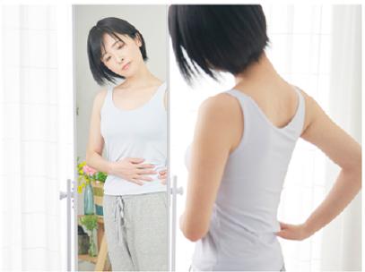 鏡の前でお腹や腰回りを気にしている女性