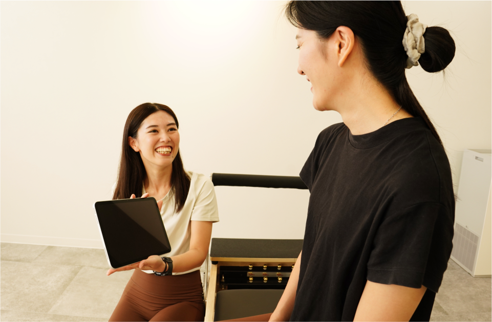 ピラティスインストラクターがタブレットを使ってレッスン内容を説明している様子